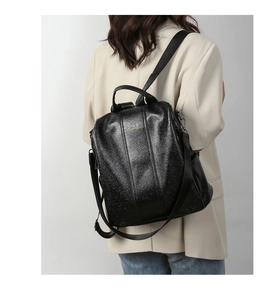 Back view of a sleek black textured leather anti-theft backpack on a model's shoulder
