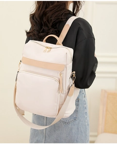 Détails latéraux d'un sac à dos bicolore crème et camel sur un modèle avec pompon chic