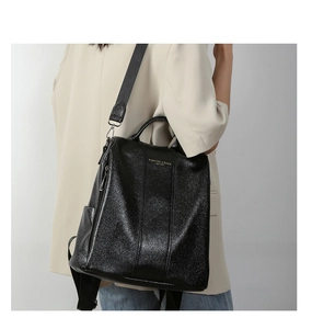Rear view of a model wearing a sleek black glossy leather backpack with gold lettering