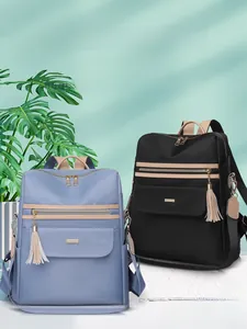 Détail du sac à dos bicolore montrant les compartiments à zip et le pompon décoratif