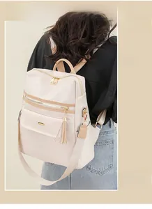 Détail d'un sac à dos bicolore avec pompon et ferrures dorées en beige et marron clair