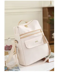 Détail du sac à dos crème avec pompons, grande capacité et finitions dorées chic