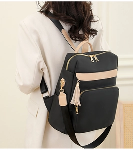 Détail d'un sac à dos en nylon noir avec accents en cuir beige porté par un mannequin