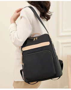 Détail d'un sac à dos en nylon noir avec des garnitures en cuir beige et un gland