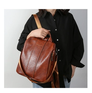 Detail of vintage brown pebble leather backpack with gold logo and adjustable straps