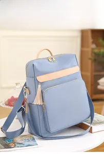 Gros plan d'un sac à dos bleu en nylon avec garniture marron et détail de pompon