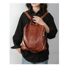 Detailed close-up of brown faux leather backpack with metallic zippers and textured finish