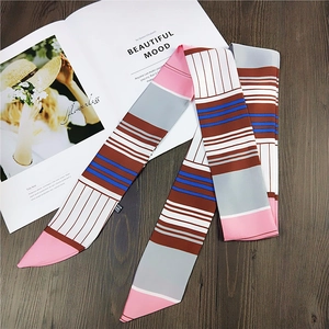 Elegant geometric stripe skinny silk scarf for women styled on a wooden tabletop