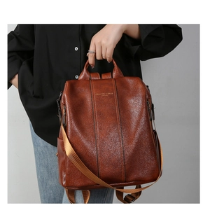 Detail of dark brown leather backpack showing fine grain texture and golden logo print