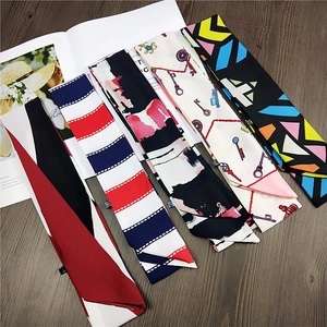 Versatile long skinny silk scarves with diverse artistic prints on a wooden surface