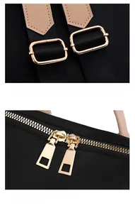 Détail de la boucle dorée et du zip sur le sac à dos noir avec sangle en cuir brun