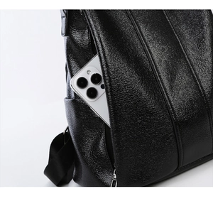 Detail of black pebbled leather backpack showing side zipper pocket with a smartphone