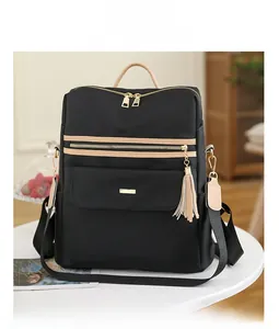 Détail du sac à dos en nylon noir imperméable avec pompons beiges et fermetures dorées