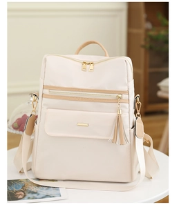 Détail du sac à dos en nylon blanc crème avec pompon et fermetures éclair dorées