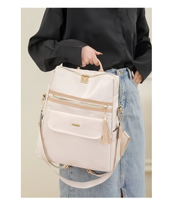 Détail du sac à dos crème avec fermetures dorées, glands en cuir et poches multiples