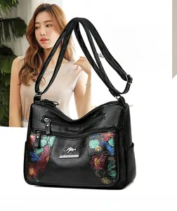 Detail of black faux leather crossbody bag with floral texture and gold kangaroo logo