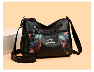 Detail view of black textured leather bag with colorful floral prints and silver kangaroo logo
