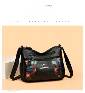 Detailed view of black litchi leather bag with floral print and kangaroo metal logo