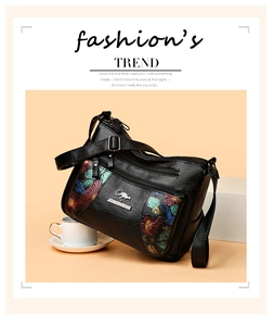 Macro detail of floral embroidery and metal kangaroo logo on black leather crossbody bag