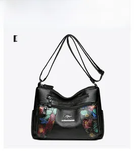 Detailed front view of black leather crossbody bag with colorful floral embroidery