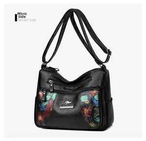 Detail view of the black soft leather crossbody bag with floral pattern and kangaroo logo
