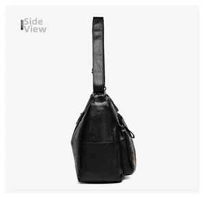 Side view showing the spacious capacity and printed details of this black leather crossbody bag