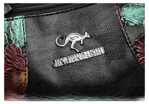 Macro shot of black leather bag with silver kangaroo logo and floral print details