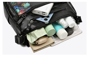 Detail view of large capacity black printed leather bag with multi-zipper compartments