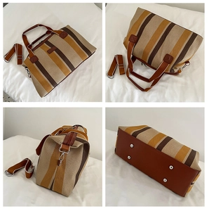 Detailweergave van gestreepte canvas tas met leren handvatten en metalen beschermvoetjes