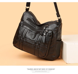Detail einer schwarzen Ledertasche mit Mehrfachreißverschlüssen und Gittersteppung