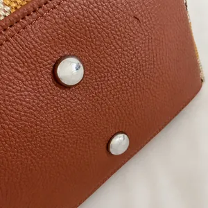 Detail van de tasbodem in litchi-leer met duurzame zilveren metalen noppen en stiksels