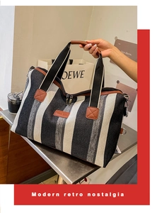 Detailopname van gestreepte canvas shopper met bruine lederen handvaten en metalen accenten