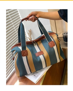 Detailopname van een gestreepte canvas shopper met bruine leren handvatten en merkpatch