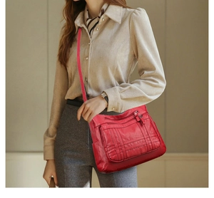Detailaufnahme der roten Handtasche mit mehreren Reißverschlusstaschen und Steppmuster-Design