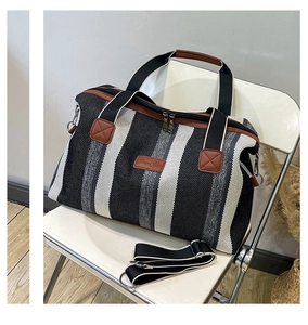 Detail van gestreepte canvas shopper met bruine leren handvatten en schouderriem