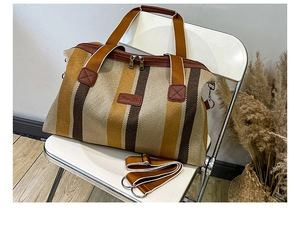 Detail van de grote gestreepte canvas tas met leren logo en verstelbare schouderband