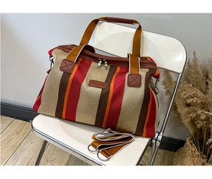 Detail van een gestreepte canvas shopper met leren logo en afneembare schouderriem