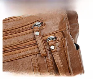 Detailansicht der braunen Tasche mit Litschi-Maserung und doppelten Silberreißverschlüssen