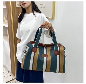 Detail van grote gestreepte canvas shopper met metalen rits en bruine lederen accenten