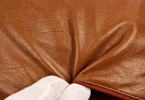 Close-up of premium brown litchi pattern leather with soft texture and fine zipper detail