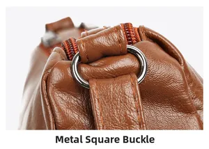 Detail of brown leather crossbody bag with silver hardware rings and double zipper stitching
