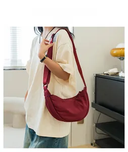 Model wearing a burgundy crescent nylon crossbody bag with matching wide fabric strap