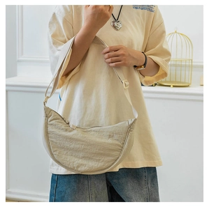 Detailed close-up of beige nylon crescent crossbody bag with zipper and adjustable strap