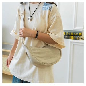 Detail of minimalist beige nylon crescent bag with adjustable wide shoulder strap