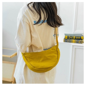 Detail showing a yellow nylon crescent crossbody bag worn by a model in casual setting