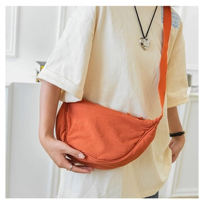 Detail of an orange nylon crescent crossbody bag with adjustable wide fabric strap