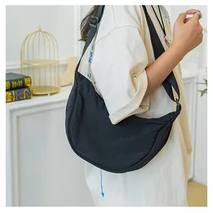 Detail of minimalist black nylon crescent crossbody bag featuring adjustable wide strap