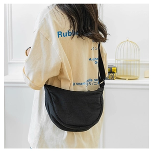 Detail of adjustable wide shoulder strap on a black nylon crescent crossbody bag