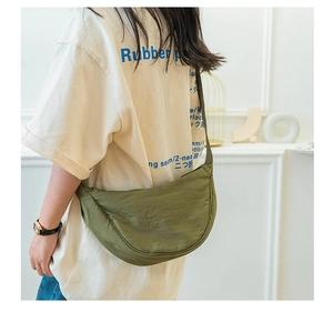 Detailed view of an army green crescent nylon crossbody bag worn on a model's back