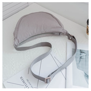 Close-up of minimalist nylon crescent crossbody bag with adjustable wide strap and zipper detail